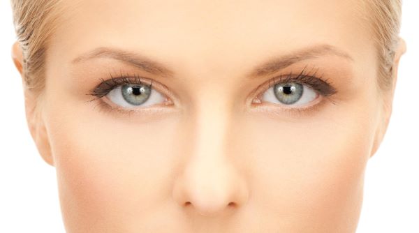 Close dos lindos olhos azuis de uma jovem que passou por blefaroplastia não cirúrgica.